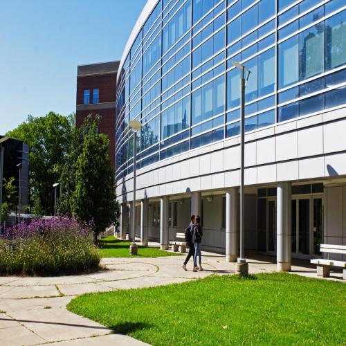 Two students walking towards Summerlee Science Complex in the Spring time.