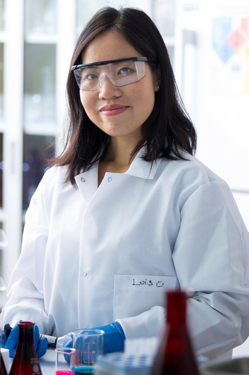 Girl in lab smiling wearing safety glasses